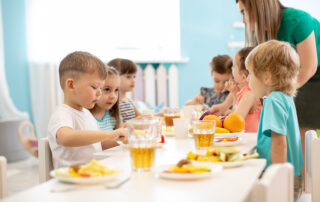 Kindergartenkinder essen und trinken gemeinsam am Tisch