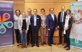 Gruppenfoto zwischen Aufstellern von Teilnehmenden einer Fachtagung