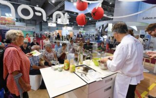 Ein Koch bereitet vor einer sitzenden Zuschauerschaft Essen zu
