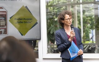 Dörthe Hennemann (DGE Sektion Niedersachsen) während eines Vortrags mit Mikrofon und blauer Mappe.