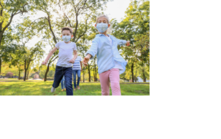 Laufende Kinder im Grünen mit Mund-Nasen-Schutz
