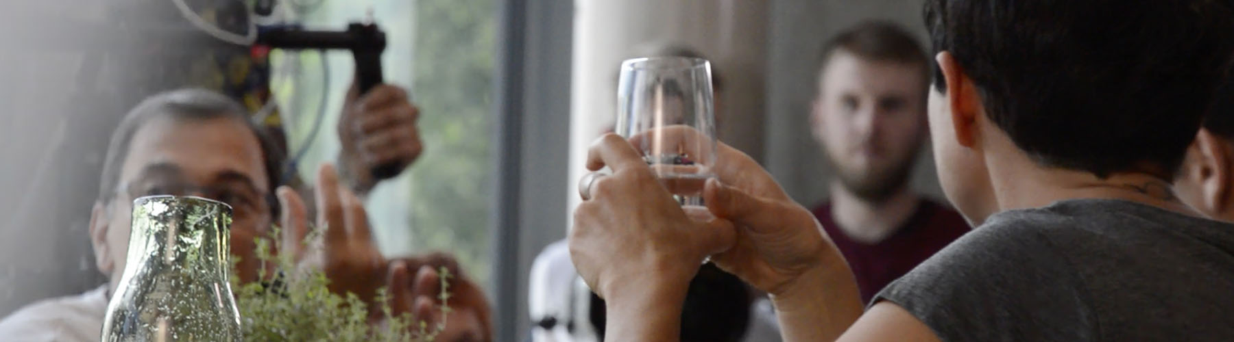 Gruppentisch in einem Restaurant, wobei die Person im Vordergrund ein Glas hält