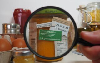 Verschiedene Lebensmittel und Vergrößerung einer Rückseite mit verschiedenen Aufklebern zum Mindesthaltbarkeitsdatum