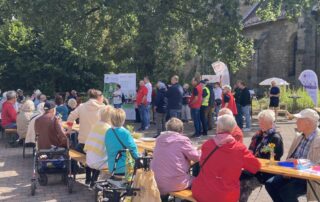 Menschen sitzen am langen Tisch im Freien